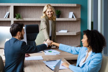 Ofisteki bilgisayar masasında oturan çok ırklı iş adamlarından oluşan bir grup - toplantı odasında dizüstü bilgisayarda çalışan çeşitli insanlar, iş ve teknoloji kavramları