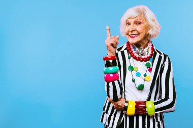 Renkli arka planda modaya uygun kıyafet portresi olan mutlu ve komik yaşlı kadın - abartılı tarzı olan genç büyükanne, yaşam tarzı, kıdemli ve yaşlı insanlar hakkında kavramlar