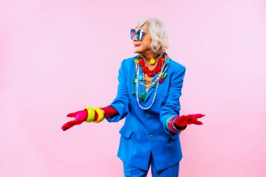 Renkli arka planda modaya uygun kıyafet portresi olan mutlu ve komik yaşlı kadın - abartılı tarzı olan genç büyükanne, yaşam tarzı, kıdemli ve yaşlı insanlar hakkında kavramlar