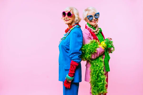 快乐而有趣的老太太们 她们穿着时尚的衣服 背景是彩色的 年轻的祖母们 有着奢华的风格 对生活方式 年资和老年人的观念 — 图库照片