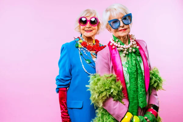 快乐而有趣的老太太们 她们穿着时尚的衣服 背景是彩色的 年轻的祖母们 有着奢华的风格 对生活方式 年资和老年人的观念 — 图库照片
