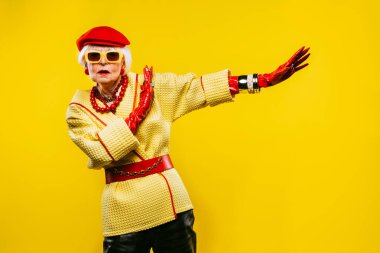 Renkli arka planda modaya uygun kıyafet portresi olan mutlu ve komik yaşlı kadın - abartılı tarzı olan genç büyükanne, yaşam tarzı, kıdemli ve yaşlı insanlar hakkında kavramlar