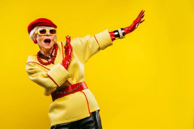 Renkli arka planda modaya uygun kıyafet portresi olan mutlu ve komik yaşlı kadın - abartılı tarzı olan genç büyükanne, yaşam tarzı, kıdemli ve yaşlı insanlar hakkında kavramlar