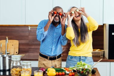 Mutfakta yemek hazırlayan çok ırklı yaşlı bir çiftin sinematik görüntüsü. Evdeki yaşam tarzı anları. Kıdem ve ilişkiler hakkındaki kavram