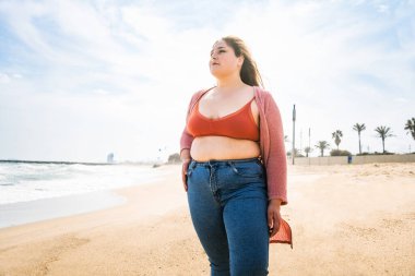 Güzel ve neşeli genç bir kadın, açık havada oldukça kilolu, kıvrımlı bir kadın, kadınlık kavramları, kadın gücü, kadın özgürlüğü, vücut pozitifliği ve vücut kabulü.