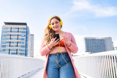 Güzel ve neşeli genç bir kadın, açık havada oldukça kilolu, kıvrımlı bir kadın, kadınlık kavramları, kadın gücü, kadın özgürlüğü, vücut pozitifliği ve vücut kabulü.