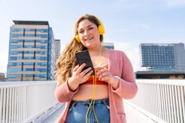 Güzel ve neşeli genç bir kadın, açık havada oldukça kilolu, kıvrımlı bir kadın, kadınlık kavramları, kadın gücü, kadın özgürlüğü, vücut pozitifliği ve vücut kabulü.