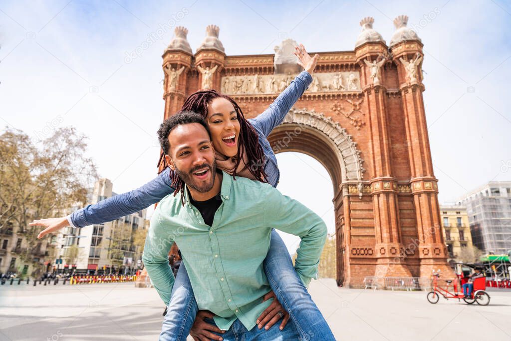 Beautiful happy hispanic latino couple of lovers dating outdoors - Tourists in Barcelona having fun during summer vacation and visiting Arc de Triumf historic landmark