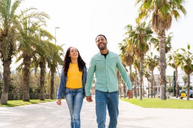 Güzel, mutlu Latin sevgililer, Barselona 'da yaz tatilinde eğlenen turistler, tropik palmiye ağaçlarıyla dolu bir parkta kaynaşan insanlar.