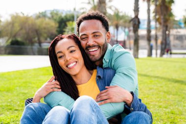 Güzel, mutlu Latin sevgililer, Barselona 'da yaz tatilinde eğlenen turistler, parkta çayırda oturan insanlar.