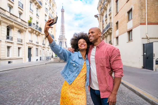 Black cheerful happy couple in love visiting Paris city centre and Eiffel Tower - African american tourists travelling in Europe and dating outdoors