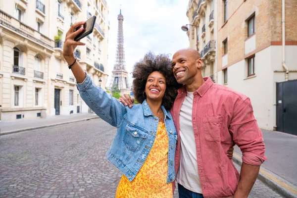 Black cheerful happy couple in love visiting Paris city centre and Eiffel Tower - African american tourists travelling in Europe and dating outdoors