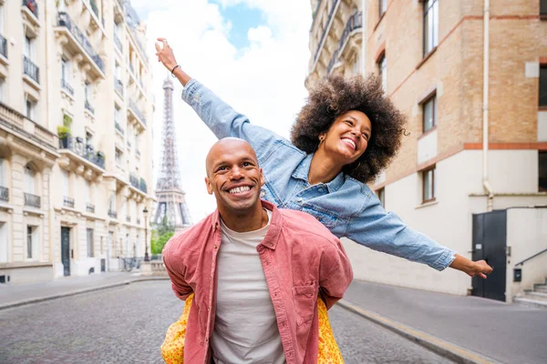 Black cheerful happy couple in love visiting Paris city centre and Eiffel Tower - African american tourists travelling in Europe and dating outdoors