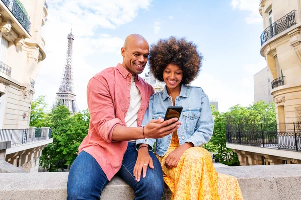 Black cheerful happy couple in love visiting Paris city centre and Eiffel Tower - African american tourists travelling in Europe and dating outdoors