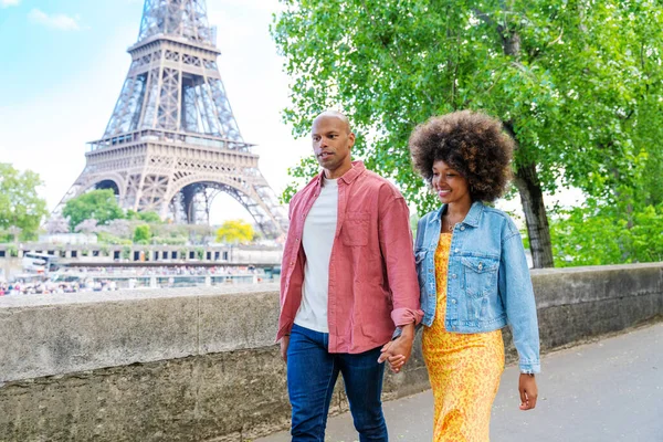 Black cheerful happy couple in love visiting Paris city centre and Eiffel Tower - African american tourists travelling in Europe and dating outdoors