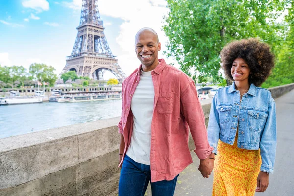 Black cheerful happy couple in love visiting Paris city centre and Eiffel Tower - African american tourists travelling in Europe and dating outdoors