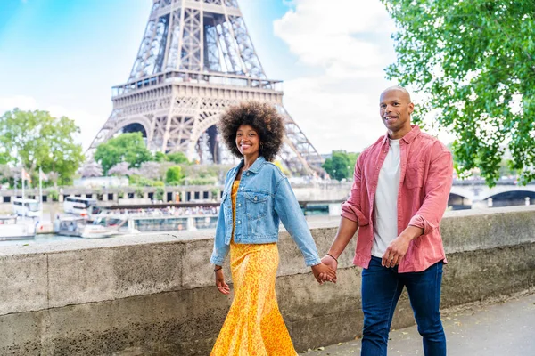 Black cheerful happy couple in love visiting Paris city centre and Eiffel Tower - African american tourists travelling in Europe and dating outdoors