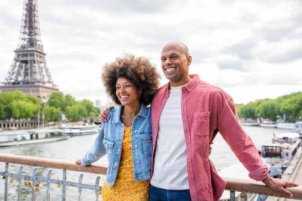 Black cheerful happy couple in love visiting Paris city centre and Eiffel Tower - African american tourists travelling in Europe and dating outdoors