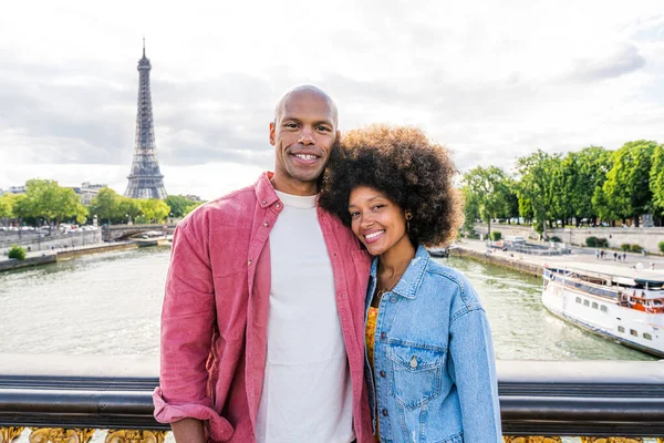 Black cheerful happy couple in love visiting Paris city centre and Eiffel Tower - African american tourists travelling in Europe and dating outdoors