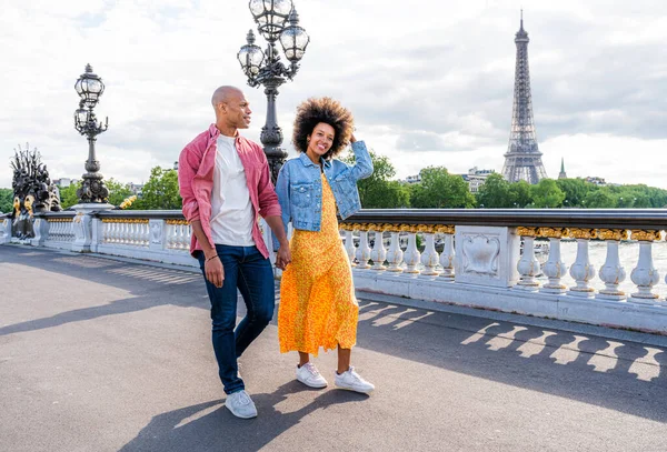 Black cheerful happy couple in love visiting Paris city centre and Eiffel Tower - African american tourists travelling in Europe and dating outdoors