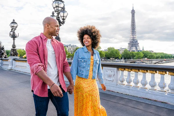 Black cheerful happy couple in love visiting Paris city centre and Eiffel Tower - African american tourists travelling in Europe and dating outdoors