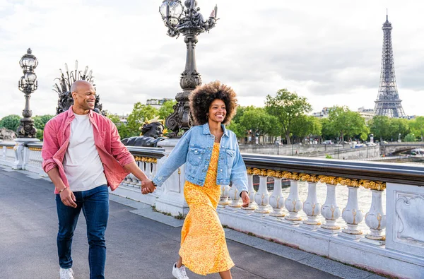 Black cheerful happy couple in love visiting Paris city centre and Eiffel Tower - African american tourists travelling in Europe and dating outdoors