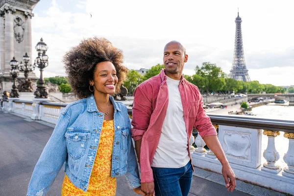 Black cheerful happy couple in love visiting Paris city centre and Eiffel Tower - African american tourists travelling in Europe and dating outdoors