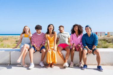 Multiethnic group of young happy friends bonding outside, having fun on summertime vacation - Multicultural cheerful people with summer clothes enjoying summer holidays, concepts about youth, friendship and positive emotion