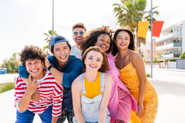 Multiethnic group of young happy friends bonding outside, having fun on summertime vacation - Multicultural cheerful people with summer clothes enjoying summer holidays, concepts about youth, friendship and positive emotion