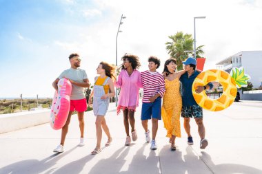 Multiethnic group of young happy friends bonding outside, having fun on summertime vacation - Multicultural cheerful people with summer clothes enjoying summer holidays, concepts about youth, friendship and positive emotion