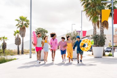 Multiethnic group of young happy friends bonding outside, having fun on summertime vacation - Multicultural cheerful people with summer clothes enjoying summer holidays, concepts about youth, friendship and positive emotion