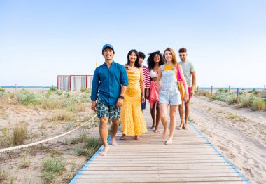 Multiethnic group of young happy friends bonding outside, having fun on summertime vacation - Multicultural cheerful people with summer clothes enjoying summer holidays, concepts about youth, friendship and positive emotion