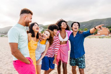 Multiethnic group of young happy friends bonding outside, having fun on summertime vacation - Multicultural cheerful people with summer clothes enjoying summer holidays, concepts about youth, friendship and positive emotion