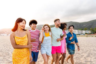 Multiethnic group of young happy friends bonding outside, having fun on summertime vacation - Multicultural cheerful people with summer clothes enjoying summer holidays, concepts about youth, friendship and positive emotion
