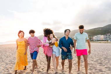Multiethnic group of young happy friends bonding outside, having fun on summertime vacation - Multicultural cheerful people with summer clothes enjoying summer holidays, concepts about youth, friendship and positive emotion