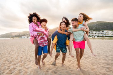 Multiethnic group of young happy friends bonding outside, having fun on summertime vacation - Multicultural cheerful people with summer clothes enjoying summer holidays, concepts about youth, friendship and positive emotion
