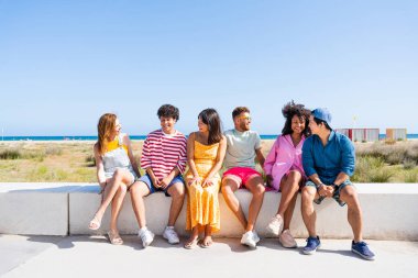 Multiethnic group of young happy friends bonding outside, having fun on summertime vacation - Multicultural cheerful people with summer clothes enjoying summer holidays, concepts about youth, friendship and positive emotion