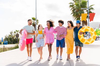Multiethnic group of young happy friends bonding outside, having fun on summertime vacation - Multicultural cheerful people with summer clothes enjoying summer holidays, concepts about youth, friendship and positive emotion