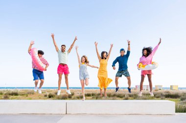 Multiethnic group of young happy friends bonding outside, having fun on summertime vacation - Multicultural cheerful people with summer clothes enjoying summer holidays, concepts about youth, friendship and positive emotion