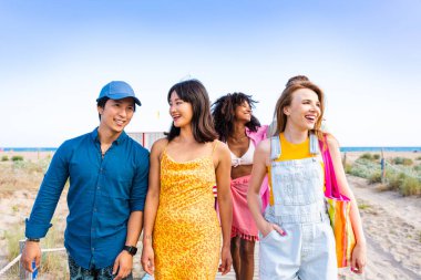Multiethnic group of young happy friends bonding outside, having fun on summertime vacation - Multicultural cheerful people with summer clothes enjoying summer holidays, concepts about youth, friendship and positive emotion