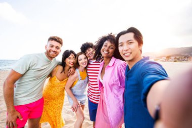 Multiethnic group of young happy friends bonding outside, having fun on summertime vacation - Multicultural cheerful people with summer clothes enjoying summer holidays, concepts about youth, friendship and positive emotion