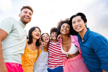 Multiethnic group of young happy friends bonding outside, having fun on summertime vacation - Multicultural cheerful people with summer clothes enjoying summer holidays, concepts about youth, friendship and positive emotion