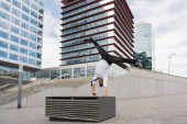 Šťastný a pohledný dospělý podnikatel v elegantním obleku dělá akrobatické triky pohyby ve městě, alternativní koncept pro obchodní reklamy s energickými a kreativními lidmi