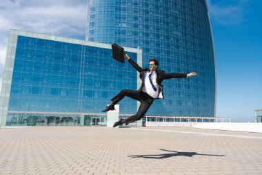 Happy and handsome adult businessman wearing elegant suit doing acrobatic trick moves in the city, alternative concept for business advertisement with energetic and creative people