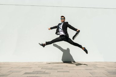 Happy and handsome adult businessman wearing elegant suit doing acrobatic trick moves in the city, alternative concept for business advertisement with energetic and creative people