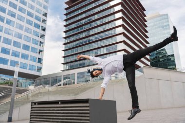Happy and handsome adult businessman wearing elegant suit doing acrobatic trick moves in the city, alternative concept for business advertisement with energetic and creative people