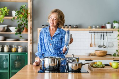 Beautiful mature senior woman at home, domestic life and leisure moments - 50-60 years old pretty female adult cooking lunch in the kitchen