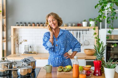 Beautiful mature senior woman at home, domestic life and leisure moments - 50-60 years old pretty female adult having a call on mobile phone