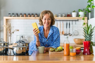 Beautiful mature senior woman at home, domestic life and leisure moments - 50-60 years old pretty female adult using smartphone to surf the web