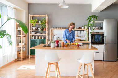 Beautiful mature senior woman at home, domestic life and leisure moments - 50-60 years old pretty female adult cooking healthy food at home in the kitchen for diet